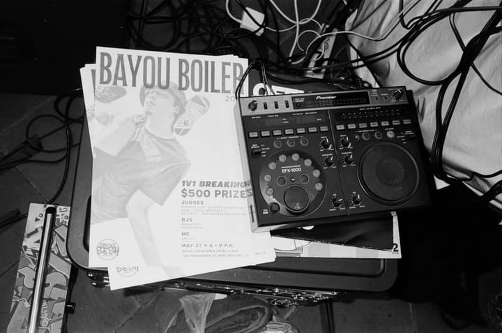 A jam flyer for "Bayou Boiler 2023" can be seen resting on top of a suitcase next to a DJ controll